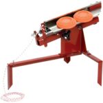 Red metal manual winch or rope puller mounted on a stand, featuring two orange handwheels and a guiding trough, with a length of rope trailing off to the side.