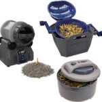 Assortment of carpentry fasteners and tools: a gray electric nailer, a blue bucket full of brass nails, and a gray coil-style fastener dispenser.