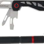 Folding knife with integrated metal tools and black grip beside a small flashlight on a keychain.