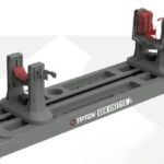 Tipton GunVise Gen II firearm rest with two red clamp assemblies mounted on a gray base, used to securely hold a gun for maintenance or cleaning.