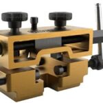 Compact wooden-bodied machinist vise with two large adjustment knobs and a threaded handle used to clamp workpieces for precise shaping.