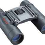 Compact Tasco 10x25 binoculars with central focusing knob, shown at an angle.