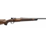 Bolt-action hunting rifle with a wooden stock and long barrel photographed from the side