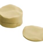 Two pats of butter on a white background, one stacked beside a separate slice of butter.