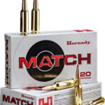 Two rifle cartridges standing upright on top of a Hornady MATCH ammunition box; other boxes and loose bullets nearby