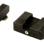 Two black plastic mechanical components on a white background: a small rectangular piece with an orange inner ring and a larger U-shaped clamp nearby.