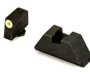 Two black plastic mechanical parts—a small rectangular block with a brass insert, and a larger wedge with a central slot.