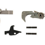 Disassembled metal tool components: two jaw-like pieces, a curved hook assembly, a small black spacer, and two short pins.