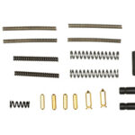 Assorted small hardware components: various coil springs, tiny compression springs, gold-colored pins, and black spacers laid out in rows.