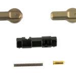Assortment of small hardware parts: two brass-toned fasteners, a black plastic connector, a metal coil spring, and a small brass pin.