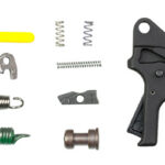 Assortment of small metal hardware parts (springs, pins, clips, screws) next to a black trigger mechanism.