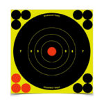 Target with a yellow background, black concentric rings, and a red bullseye; red and black shot holes clustered around the edges suggestive of a practice target.