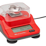 Red compact electronic jewelry scale with a clear plastic cover and metal weighing pan on top.