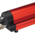 Red cylindrical power tool with three exchangeable chisel/drill bits protruding from the left, mounted on a base for bench use.
