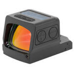 Compact red dot reflex sight with lens and two side adjustment buttons mounted on a base used for aiming.