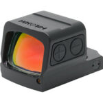 Black reflex/red-dot sight with orange-tinted lens, two side adjustment buttons, mounted on a rail for firearms