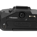 Side view of a black compact camera with a large lens on the left and control ports visible on the top and side.