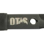 Black plastic Otis key-like tool with a grooved end and a round hole for attachment