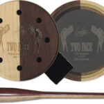 Two round wooden discs with holes and a slate insert labeled Two Face, plus a matching wooden tamper, part of a glass-over-slate smoking set.
