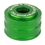 Green anodized metal spacers stacked in a cylindrical shape with 'PHASE 5 WEAPONS SYSTEMS' engraved on the top ring, a small mechanical component.