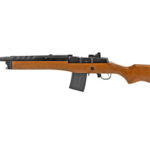 Bolt-action rifle with a wooden stock, metal barrel, and a curved detachable magazine on a white background.
