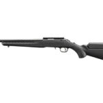 Long black rifle with a long barrel, scope rail, and adjustable buttstock seen from the side.