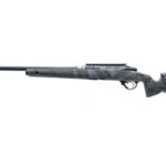 Camouflage-pattern bolt-action rifle with a long barrel and scope rail, viewed from the left.