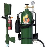 Propane weed torch system with a green ThrowFlame tank, hose, gauge, mounted wand, and red fire extinguisher nearby.