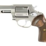 Side view of a silver revolver with a wooden grip and exposed hammer.