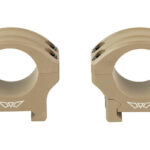 Pair of tan rifle scope rings on a white background, used to mount a scope onto a rifle.