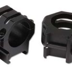 Pair of black scope rings for mounting a rifle scope, shown with screws and mounting clamps.
