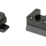 Pair of black iron firearm sights: the left front sight with a green fiber-optic insert, and the right rear sight with a notch for aiming.