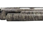 Camouflage-pattern hunting shotgun with a long barrel seen from the side and a black recoil pad at the stock end.